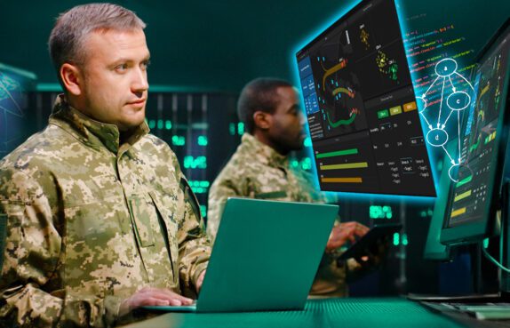 Military officer in camouflage standing in server room with laptop computer and checking data on monitors.
